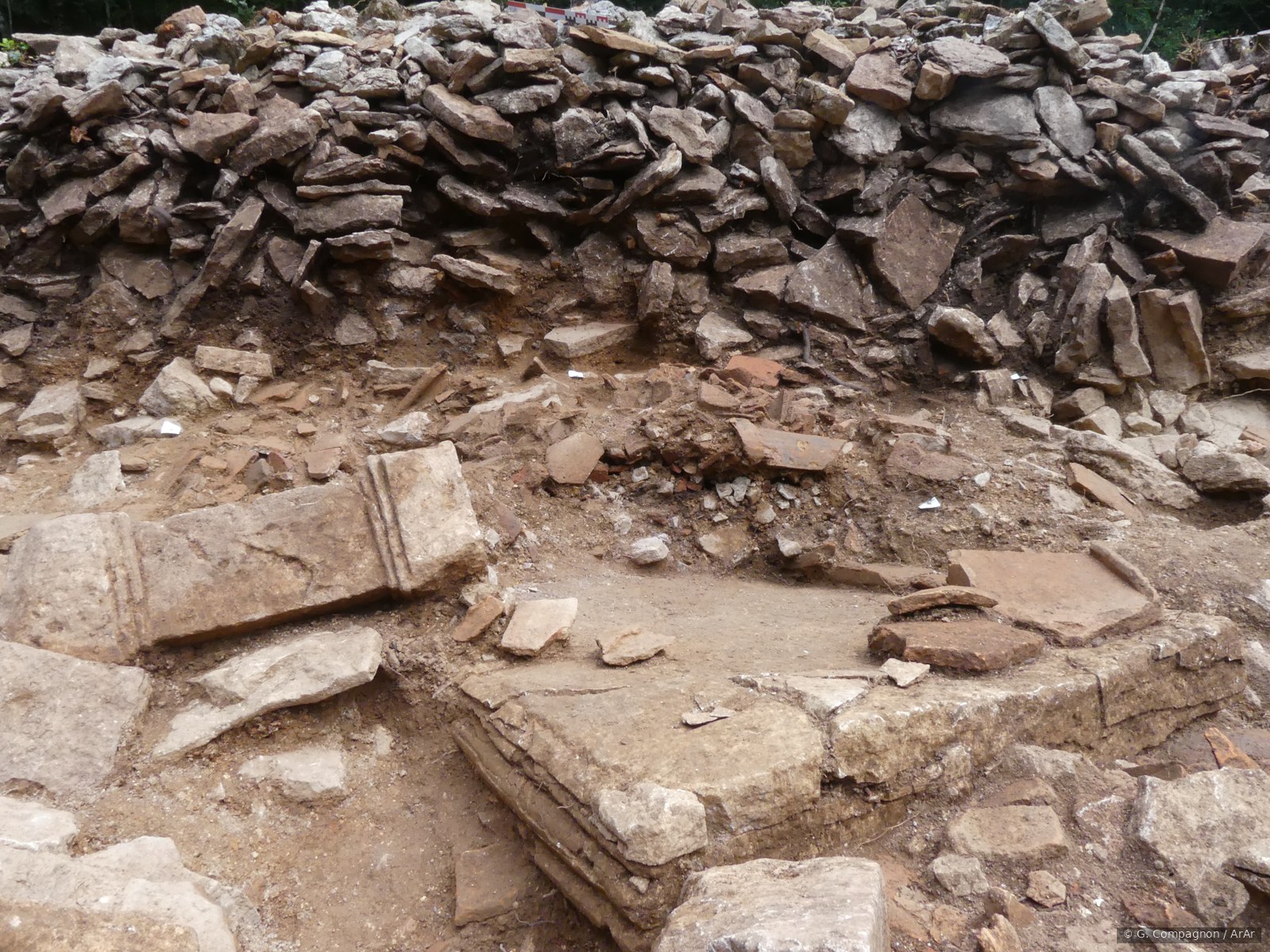 Vestiges maçonnés en cours de fouille au sanctuaire antique : pierres empilées et seuils en place.