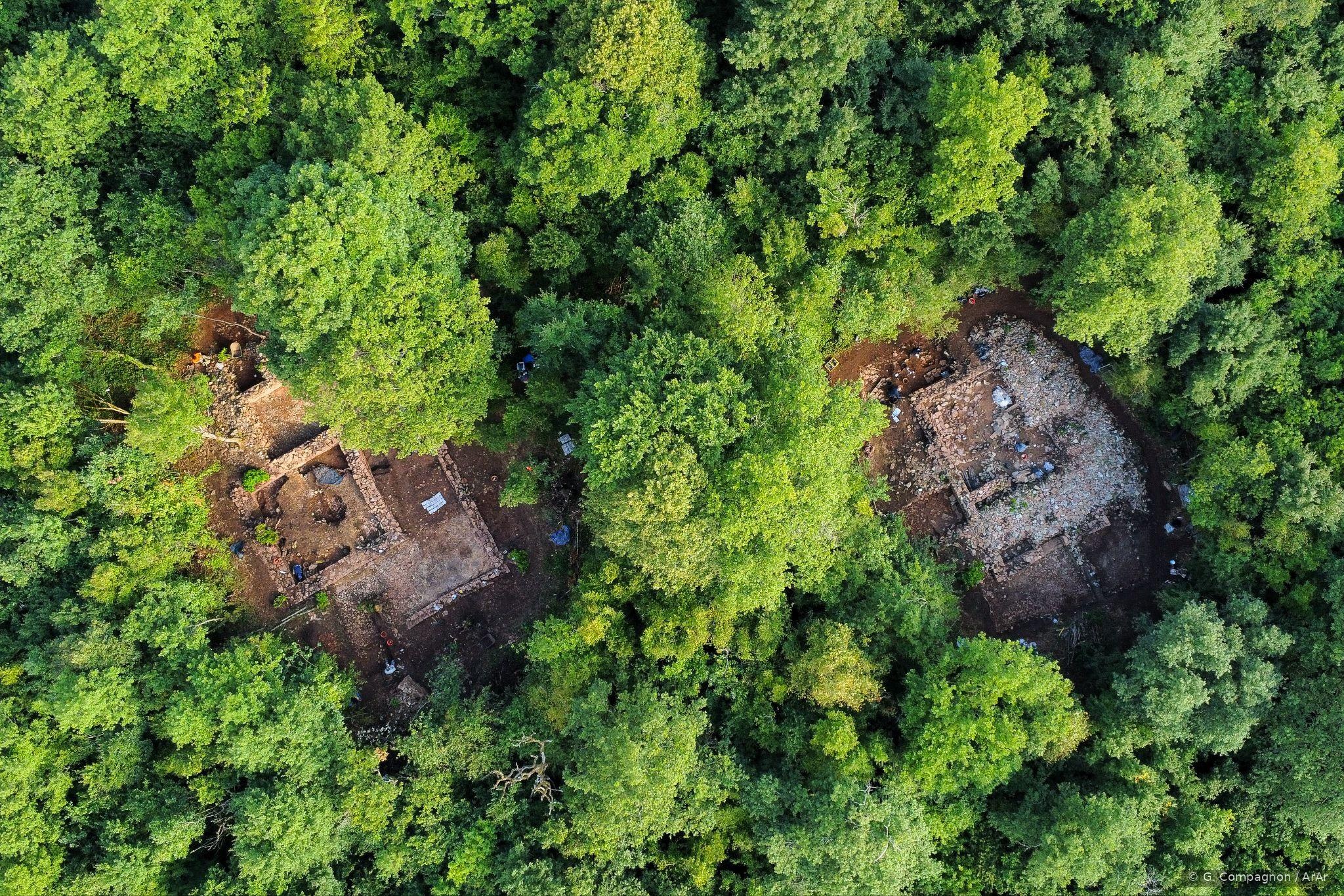 Vue aérienne par drone du site de la Roche d'Aujoux : deux monuments antiques en cours de fouille au cœur de la forêt.
